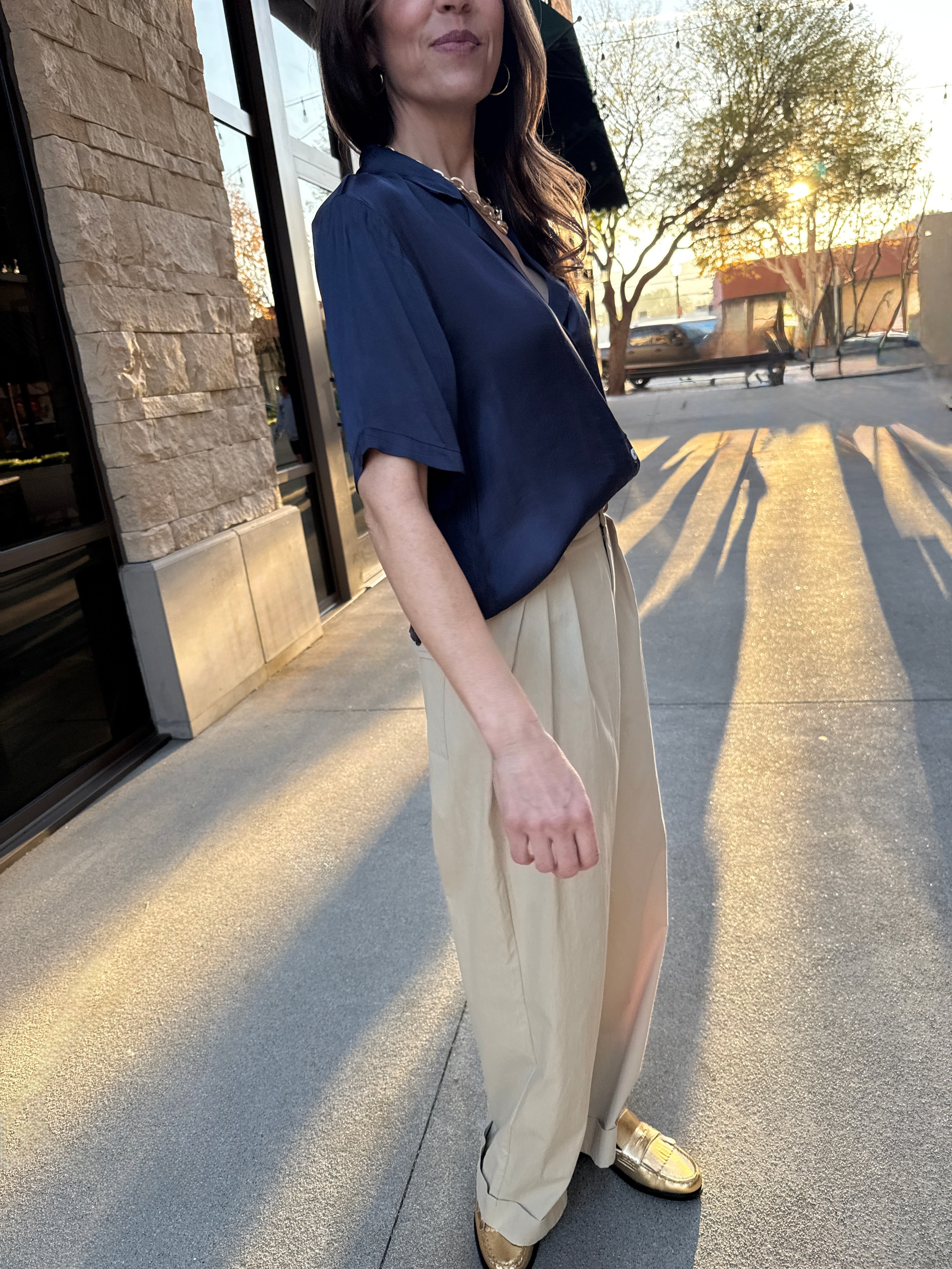 Model wearing silky, navy blue, white button up detail, blouse