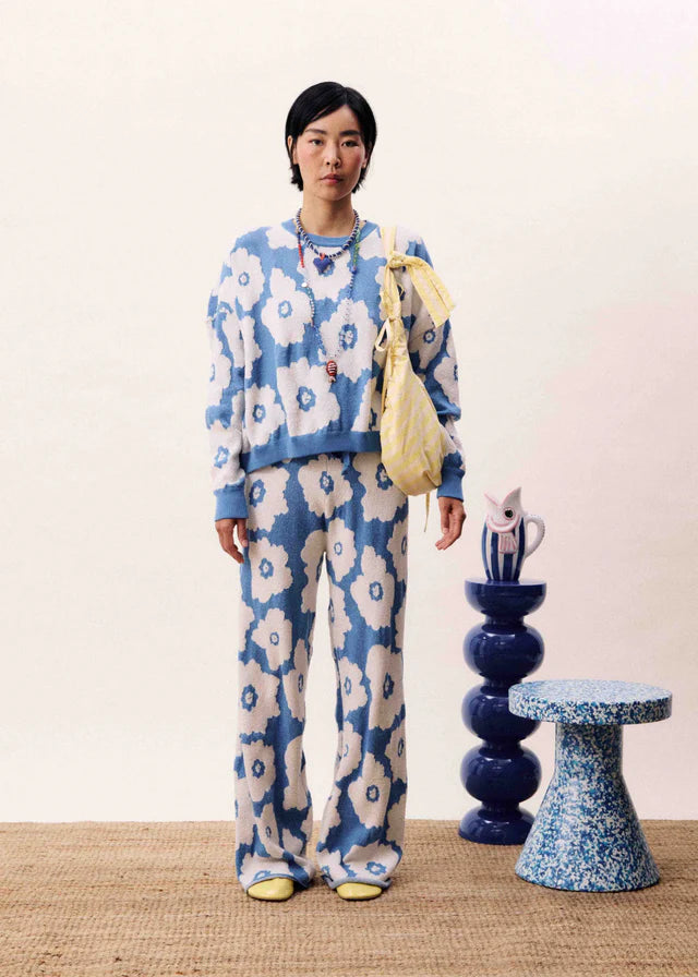 Person wearing a blue floral outfit standing in a room with decorative elements.