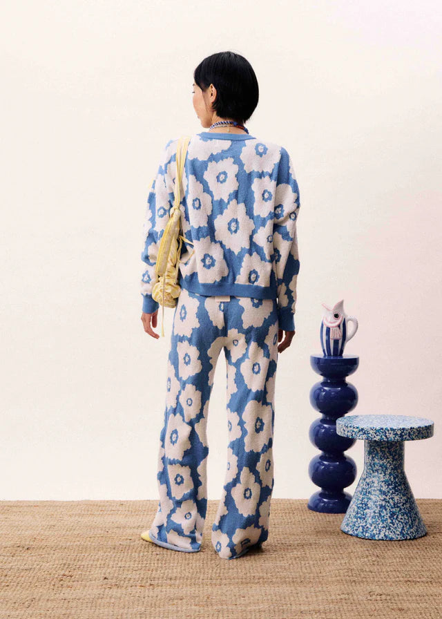 Person wearing a blue and white floral patterned outfit standing in a room with decorative elements.