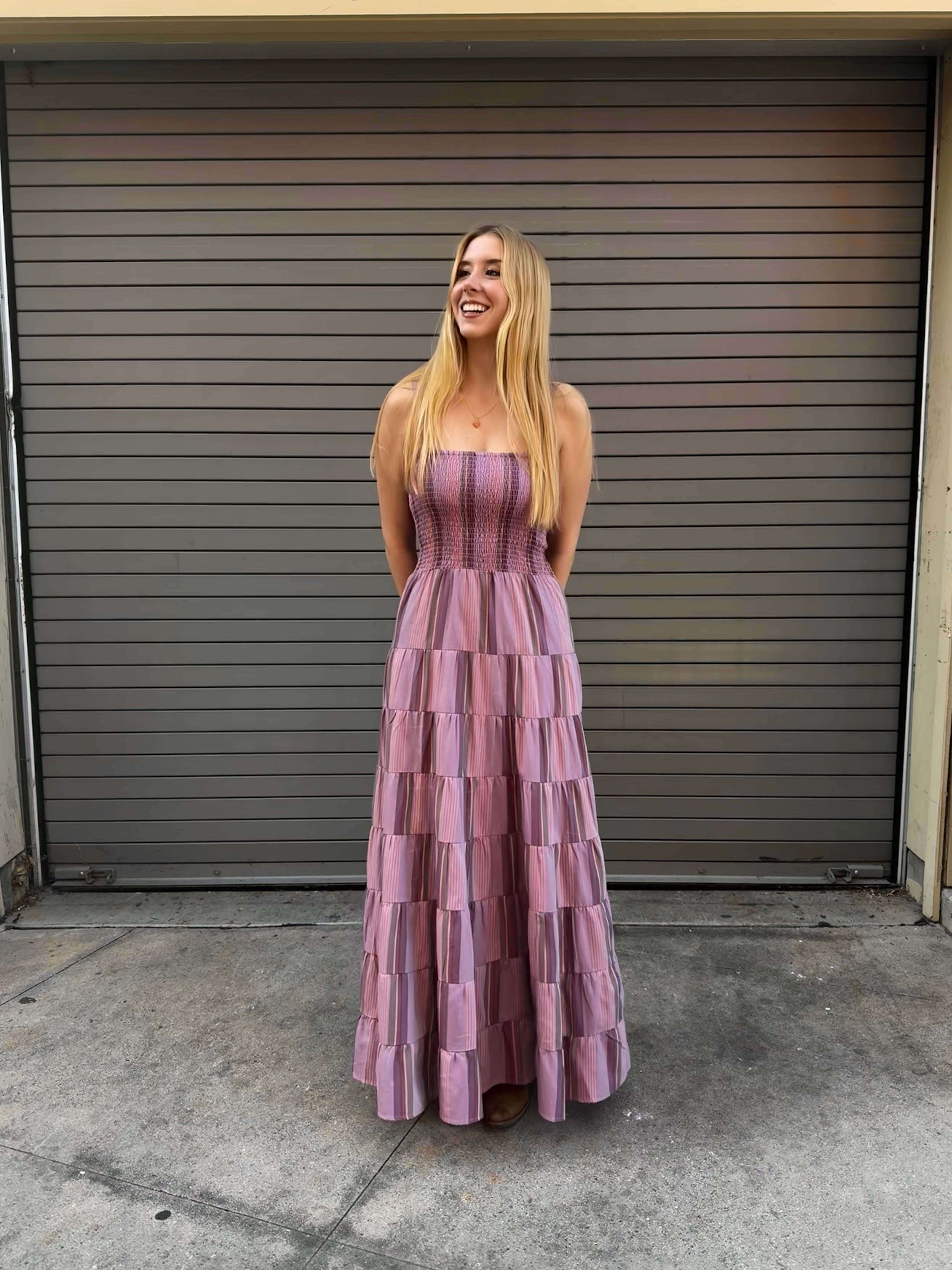 Woman in a purple tiered dress standing in front of a closed garage door.