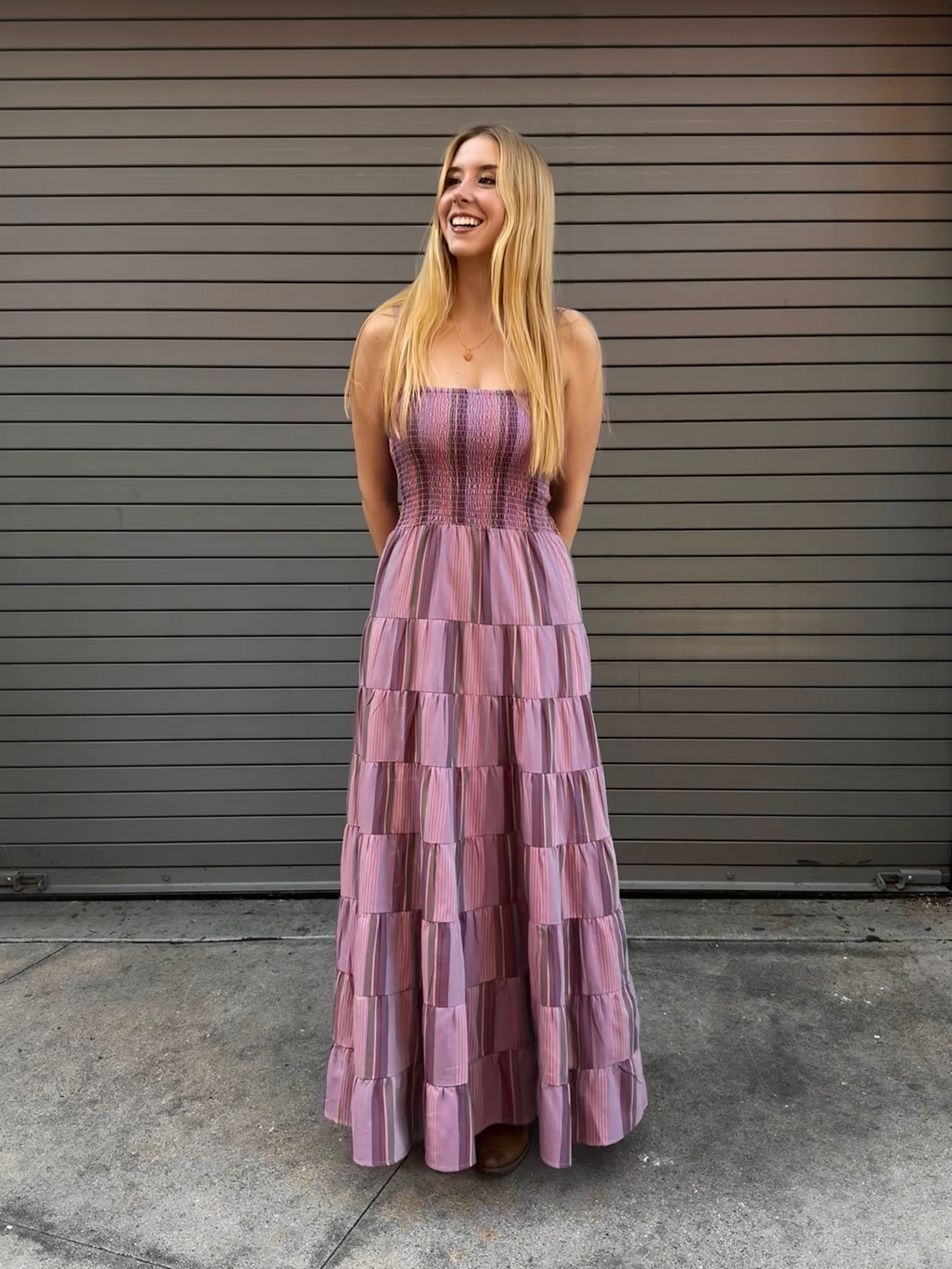 Woman in a purple tiered dress standing in front of a closed garage door.