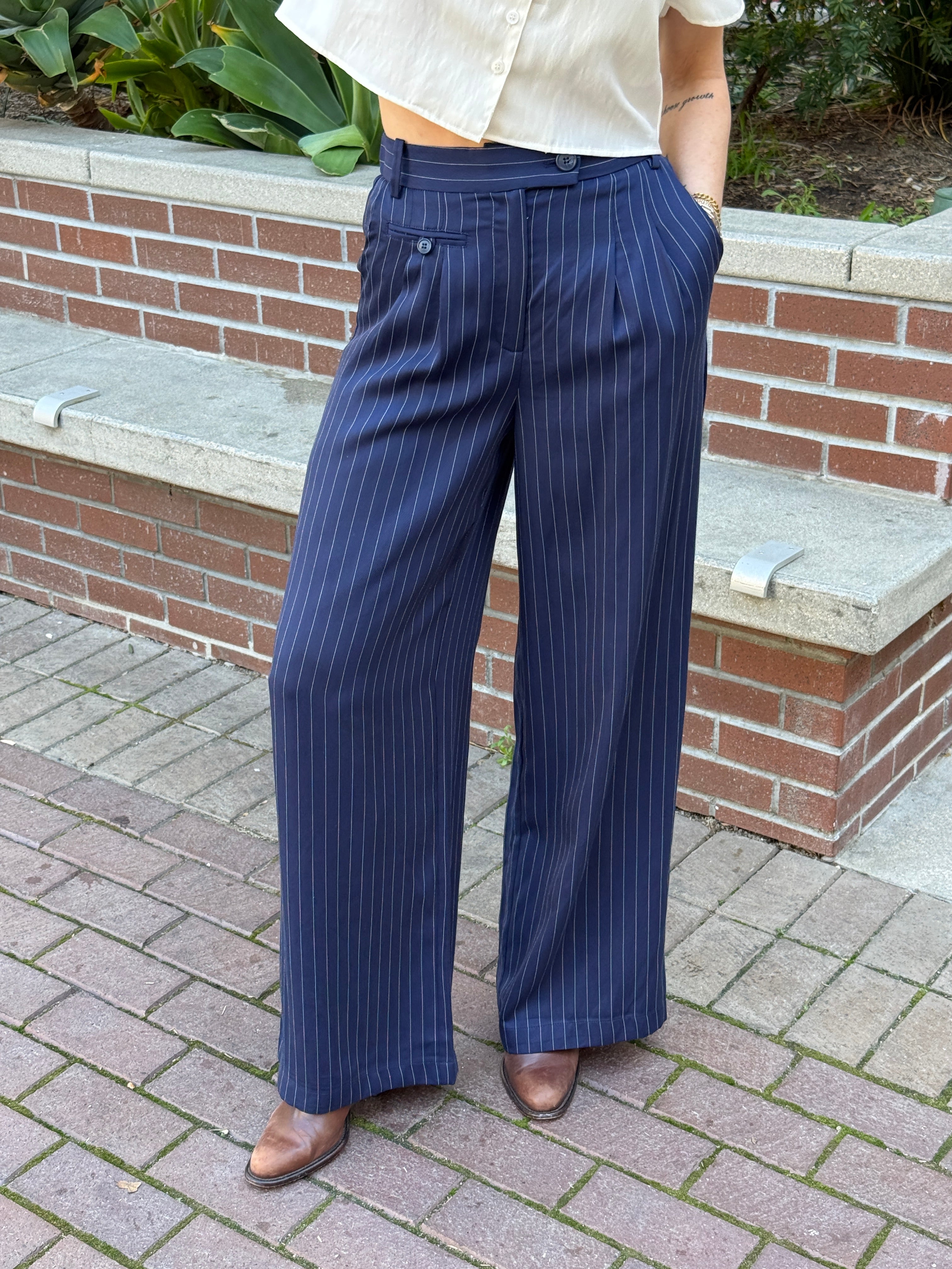 Navy pinstripe pants being worn outdoors on a paved path.