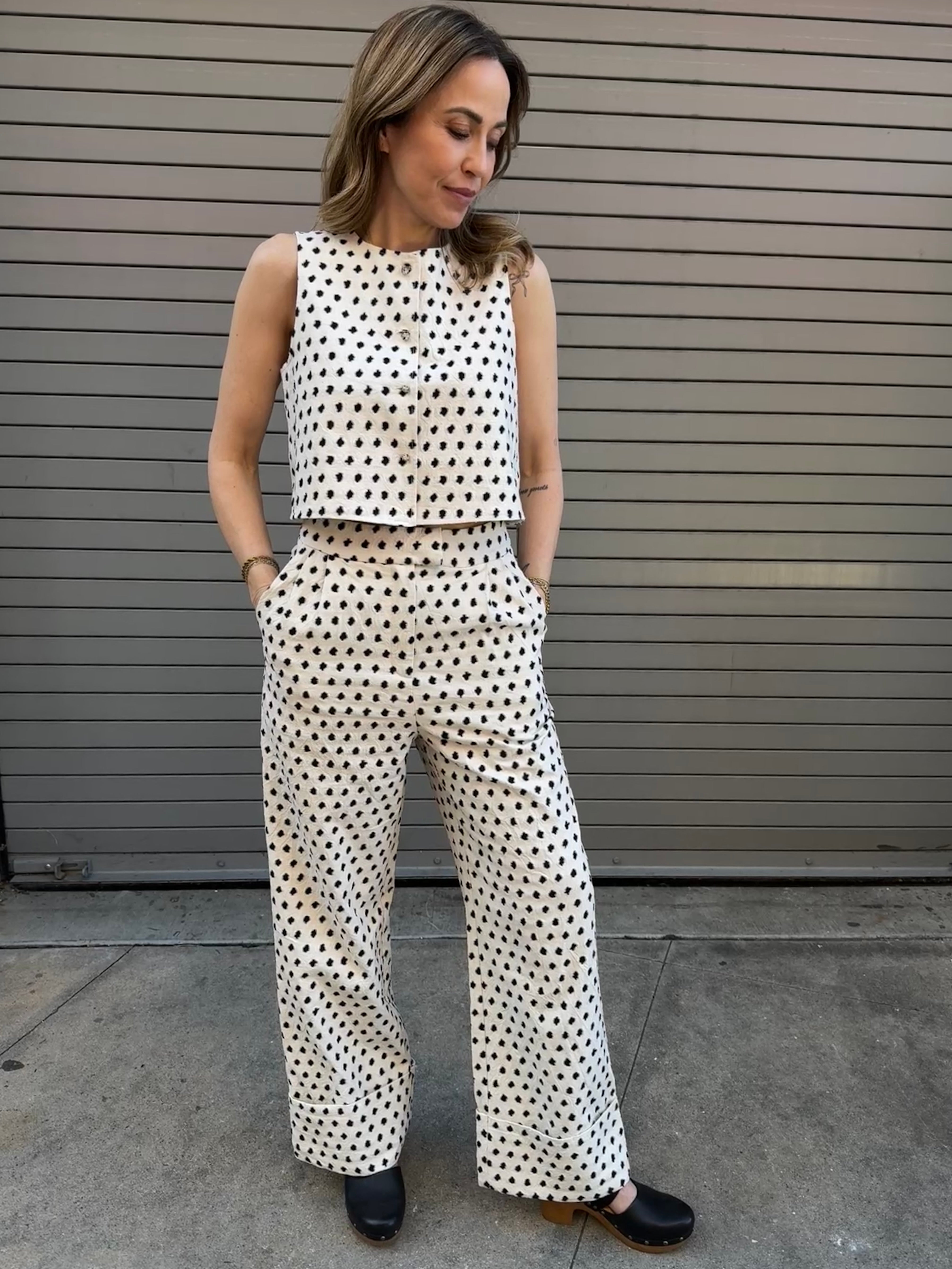 Woman wearing a polka dot outfit standing against a metallic wall.
