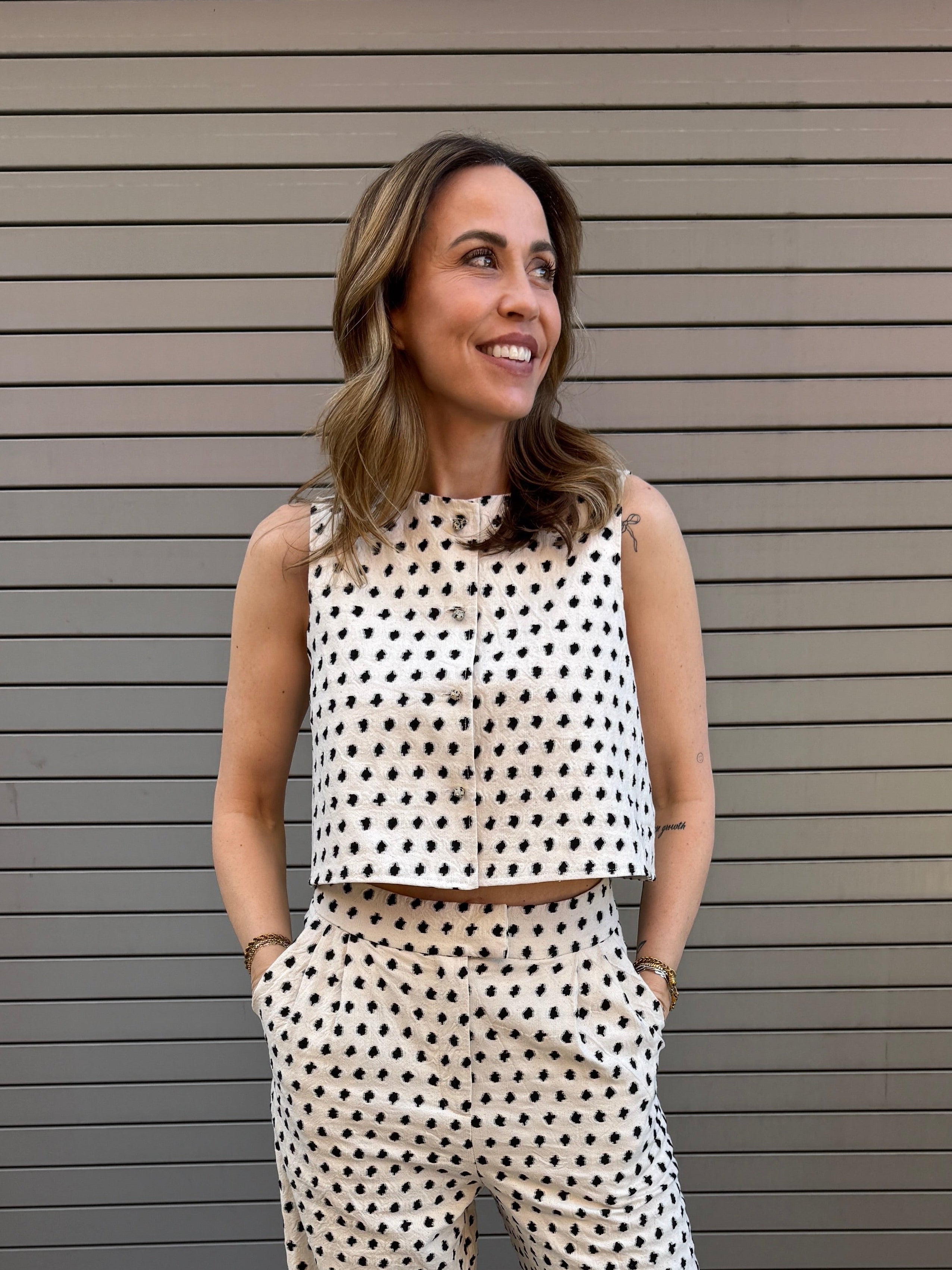 Woman wearing a polka dot outfit standing in front of a metallic shutter.