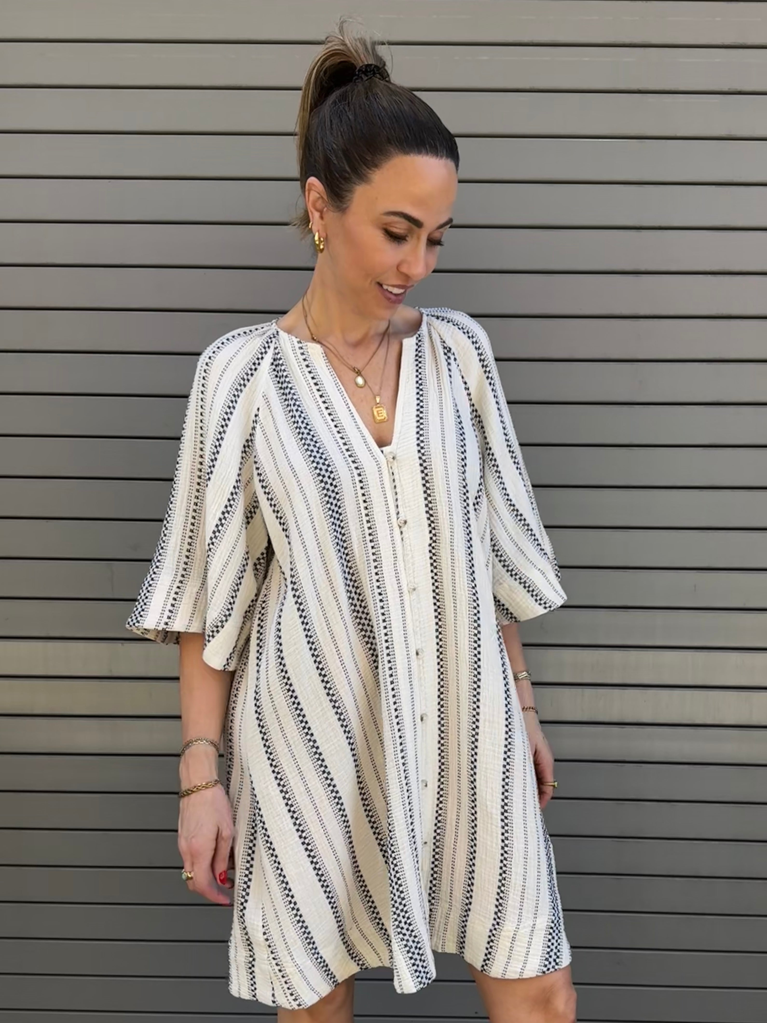 Woman wearing a striped dress against a gray background