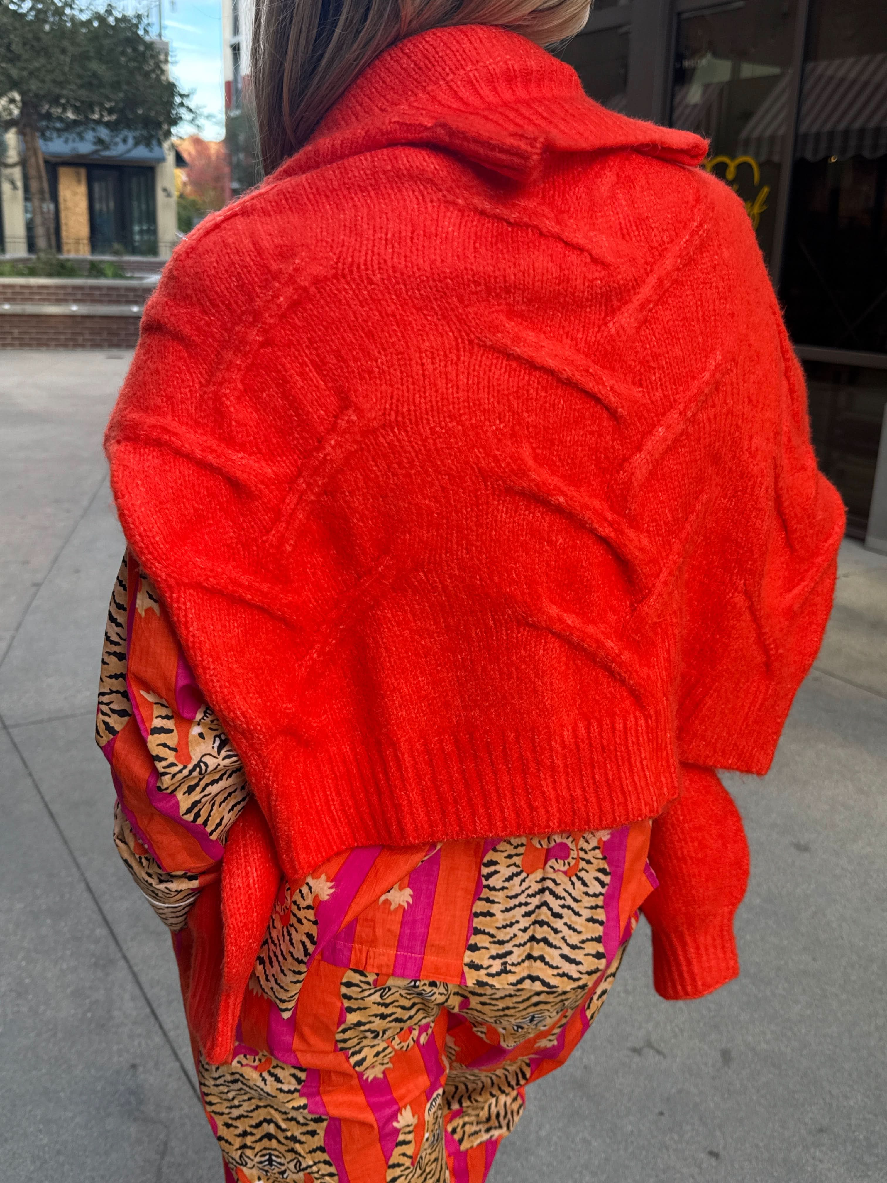 model wearing Bright Orange, fisherman, knit, high neck, sweater over her shoulder