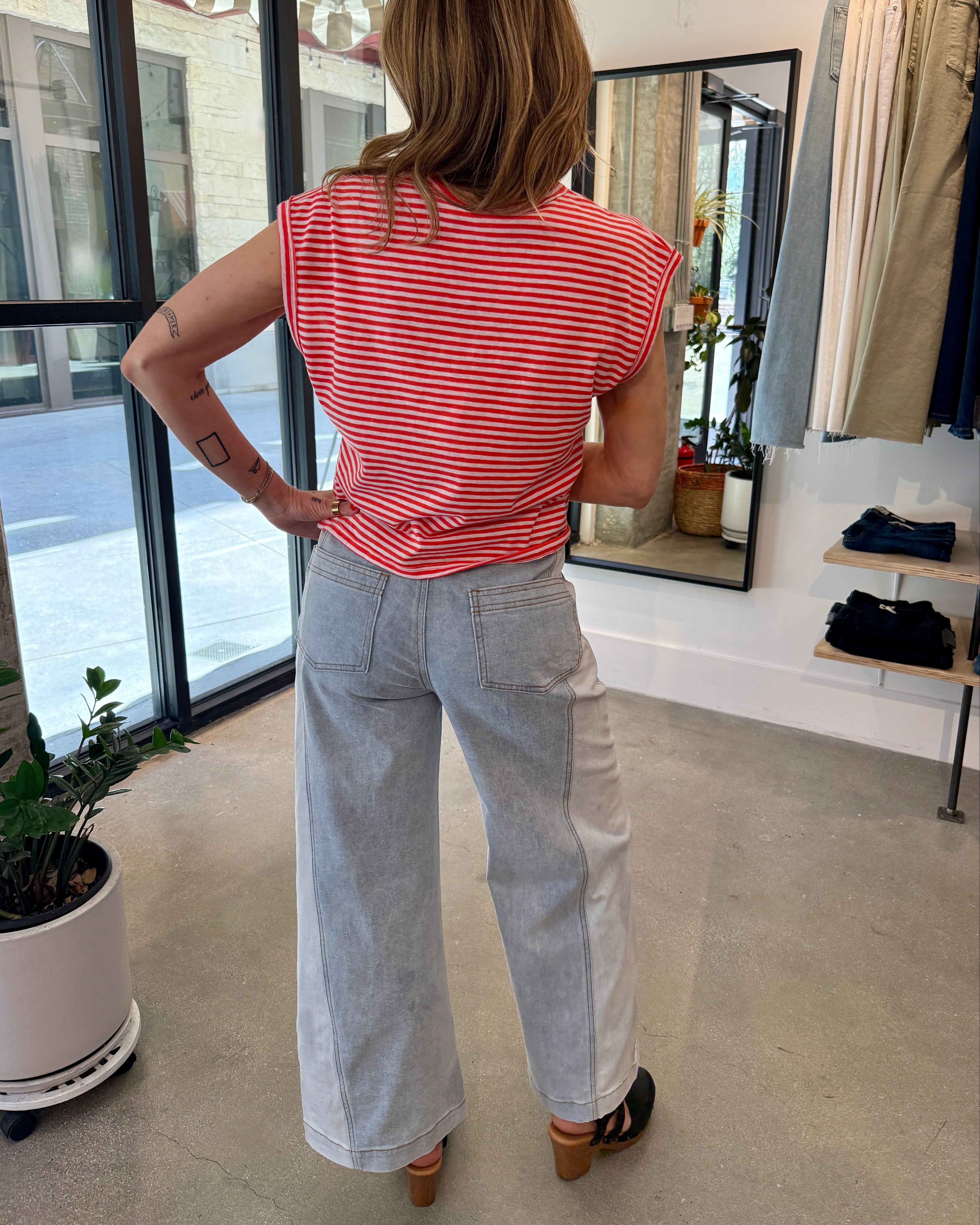 Person wearing a red and white striped shirt and light blue jeans in a store setting.