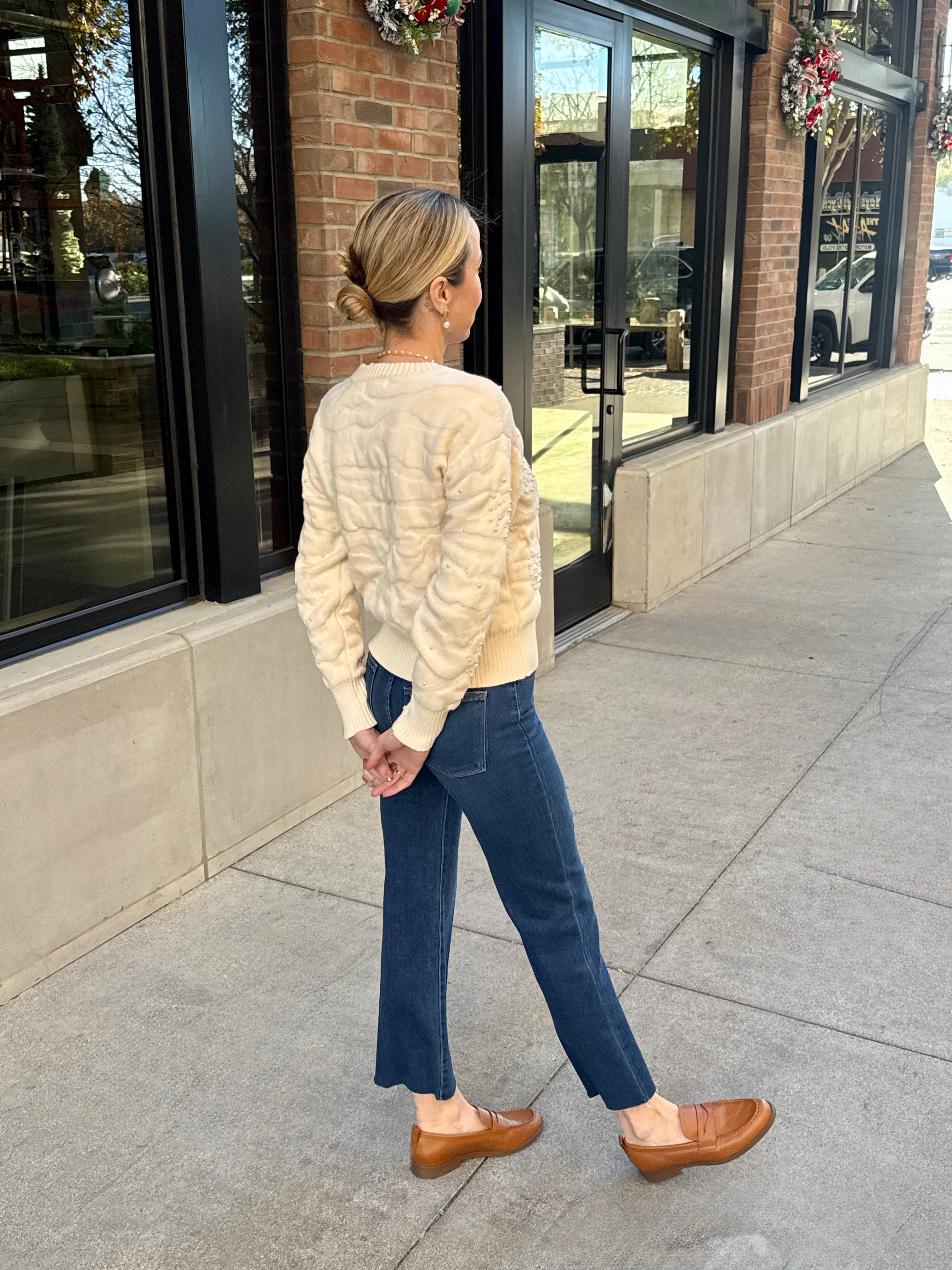 cream pearl detail winter sweater paired with blue jeans and brown loafers 