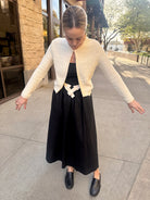 cream single button knit style cardigan with black and white bow dress