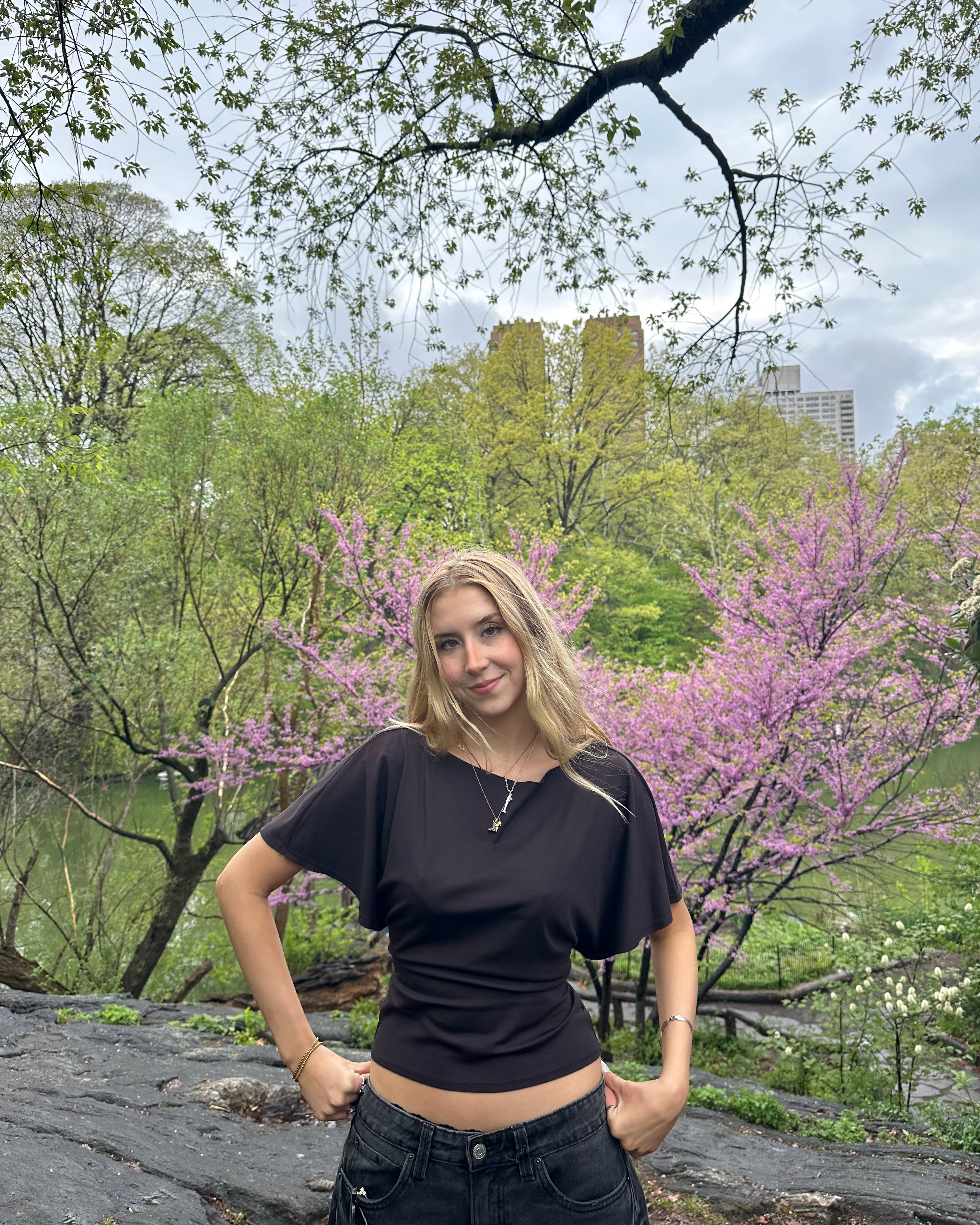 Woman standing in a park with blooming trees in the background
