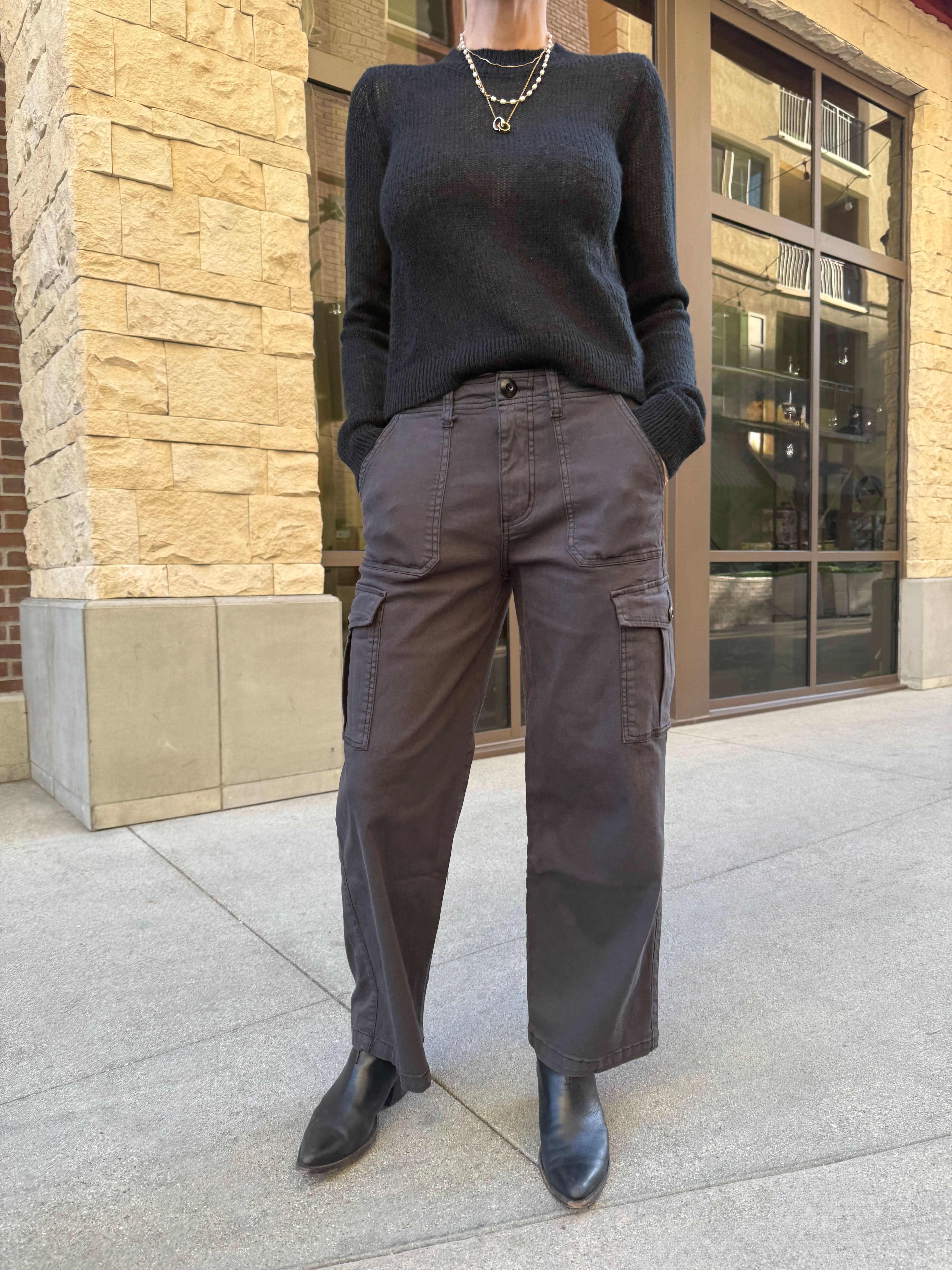 Person wearing cargo pants standing on a sidewalk.