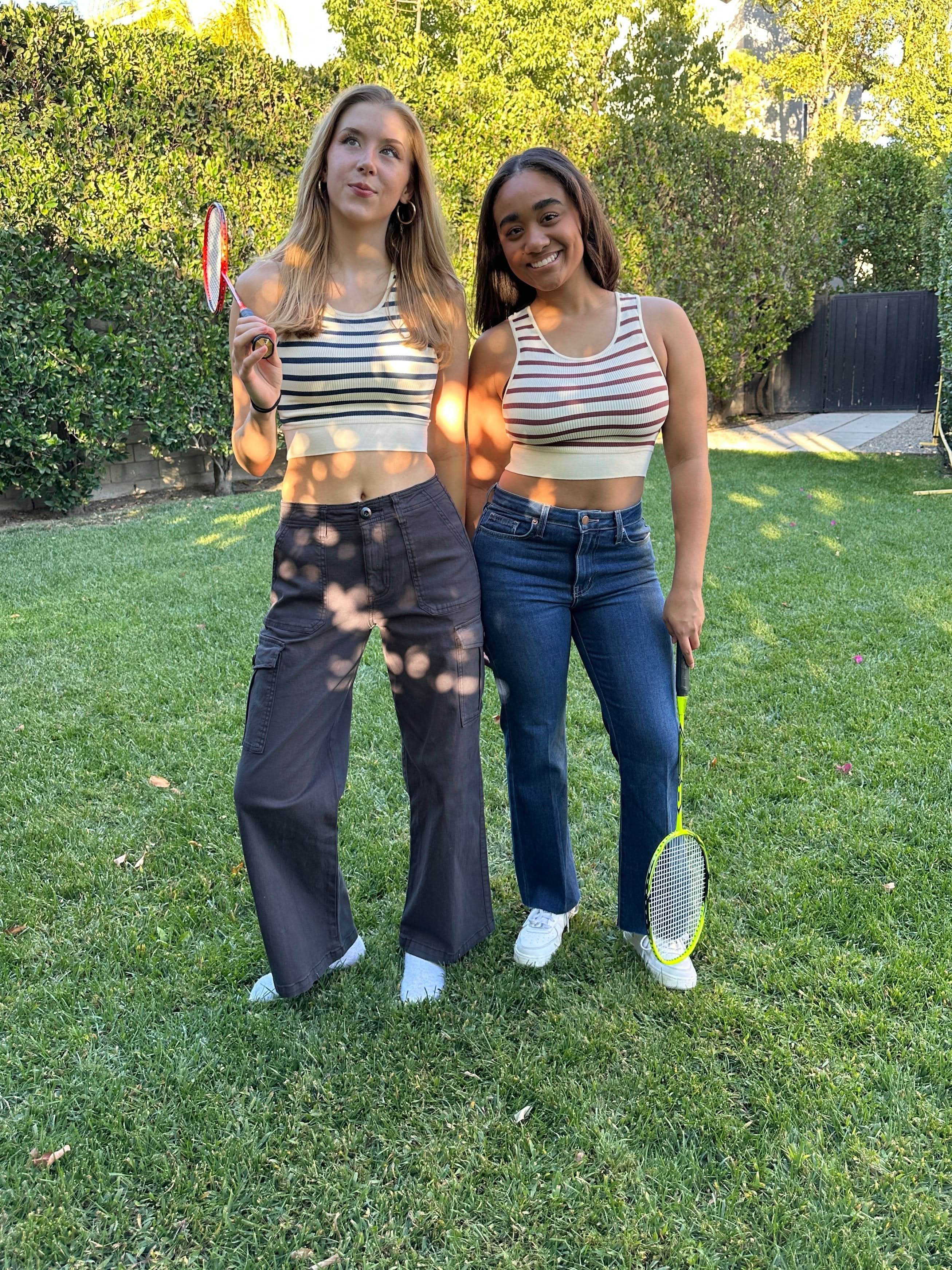 Two women wearing matching striped tops and cargo pants.