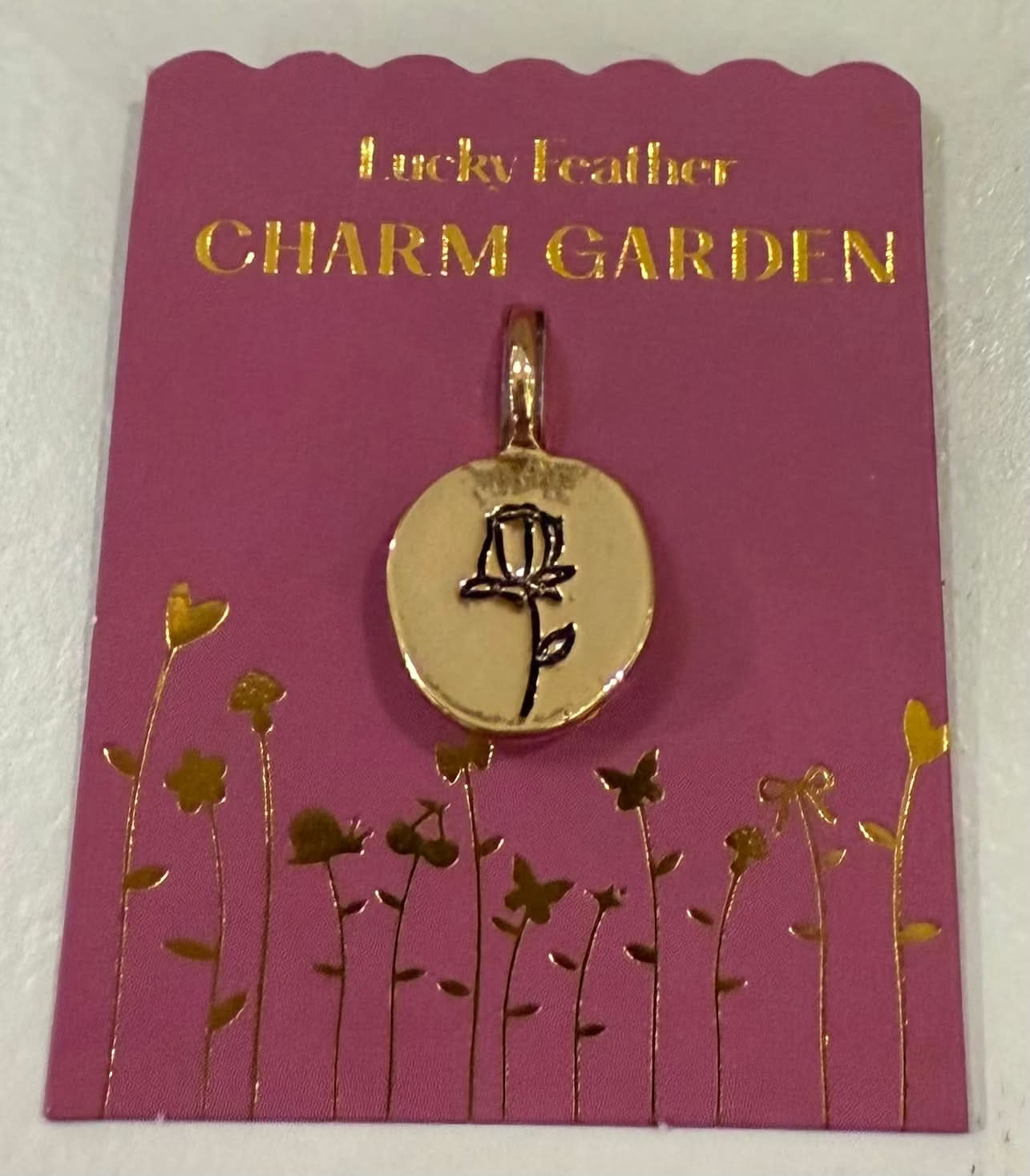 Gold charm on a 'Charm Garden' card with floral design