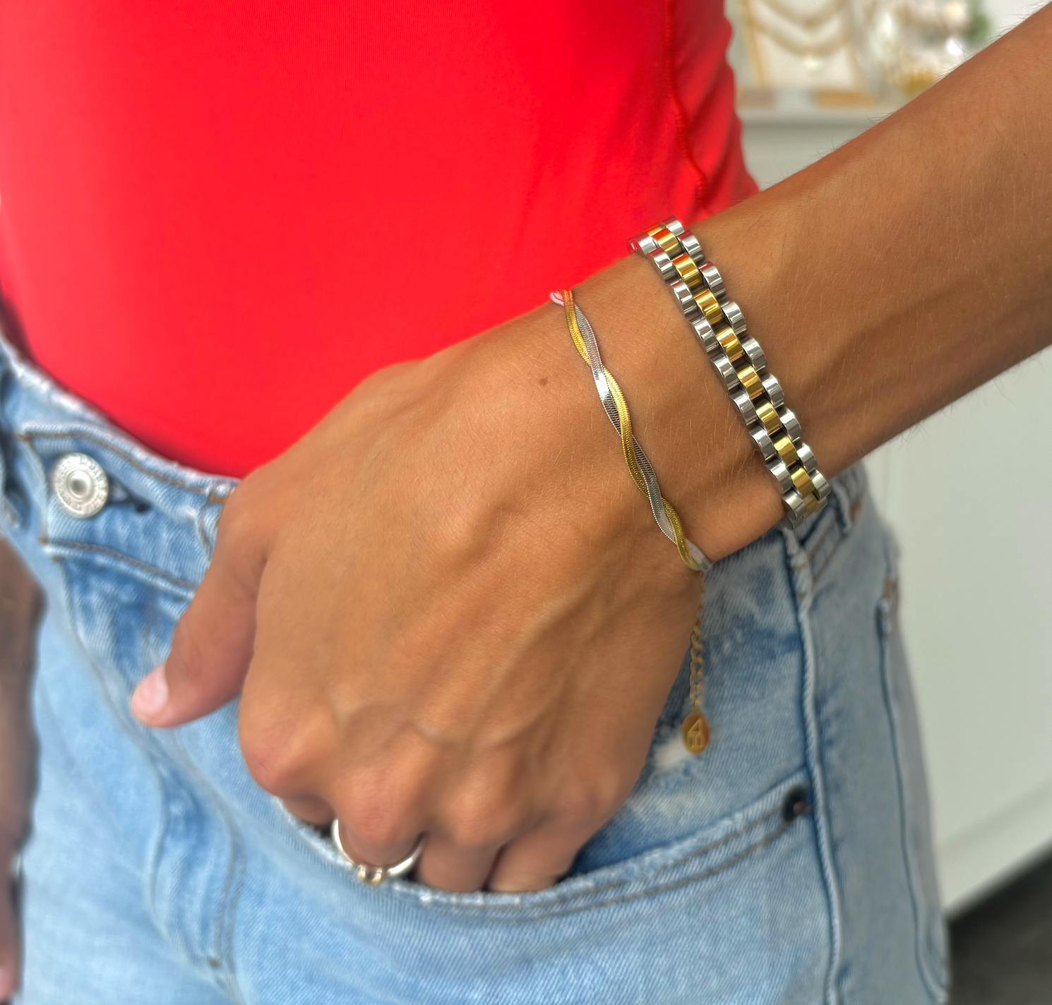 Woman wearing two mixed metal bracelets watch strap and Silver and gold twisted braid herringbone bracelet 
