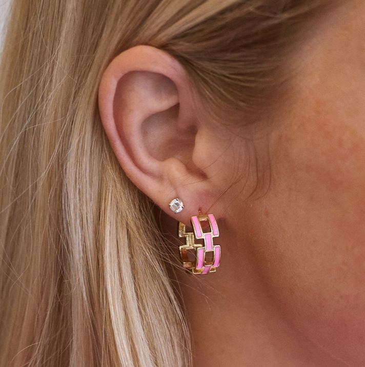 Close-up of an ear wearing a pink and gold geometric hoop earring.
