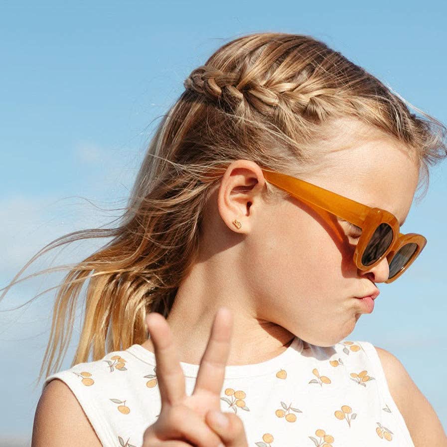 Young girl wearing orange sunglasses with a clear blue sky