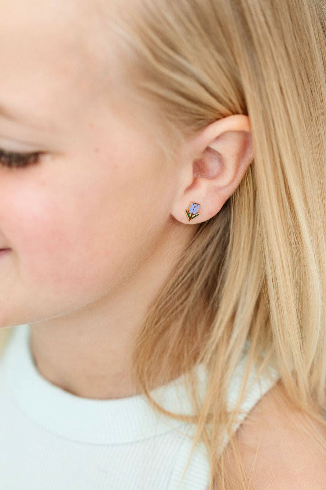 Close-up of a child wearing a small earring with a butterfly design.