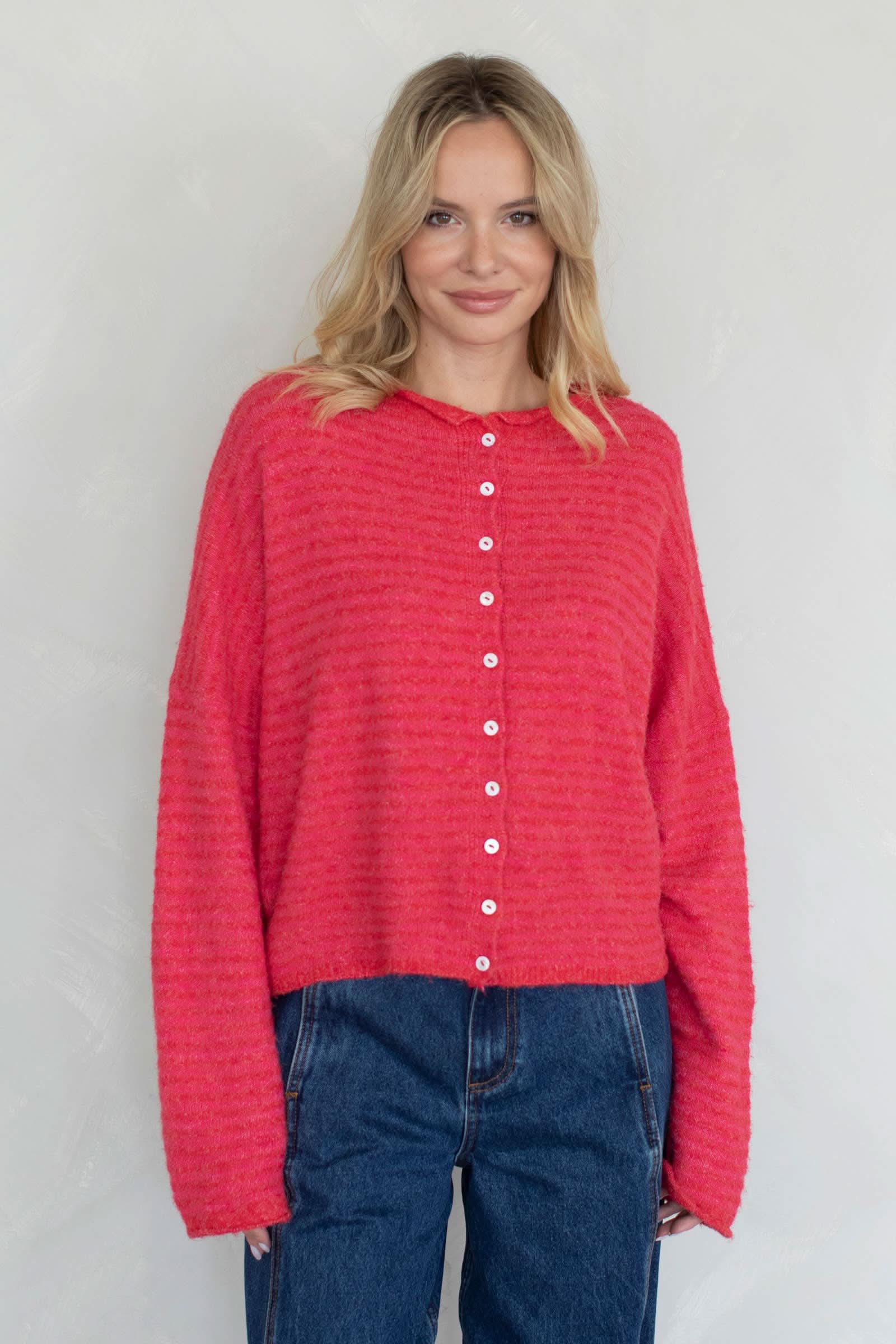 Woman wearing a red textured sweater with drop sholder and white button