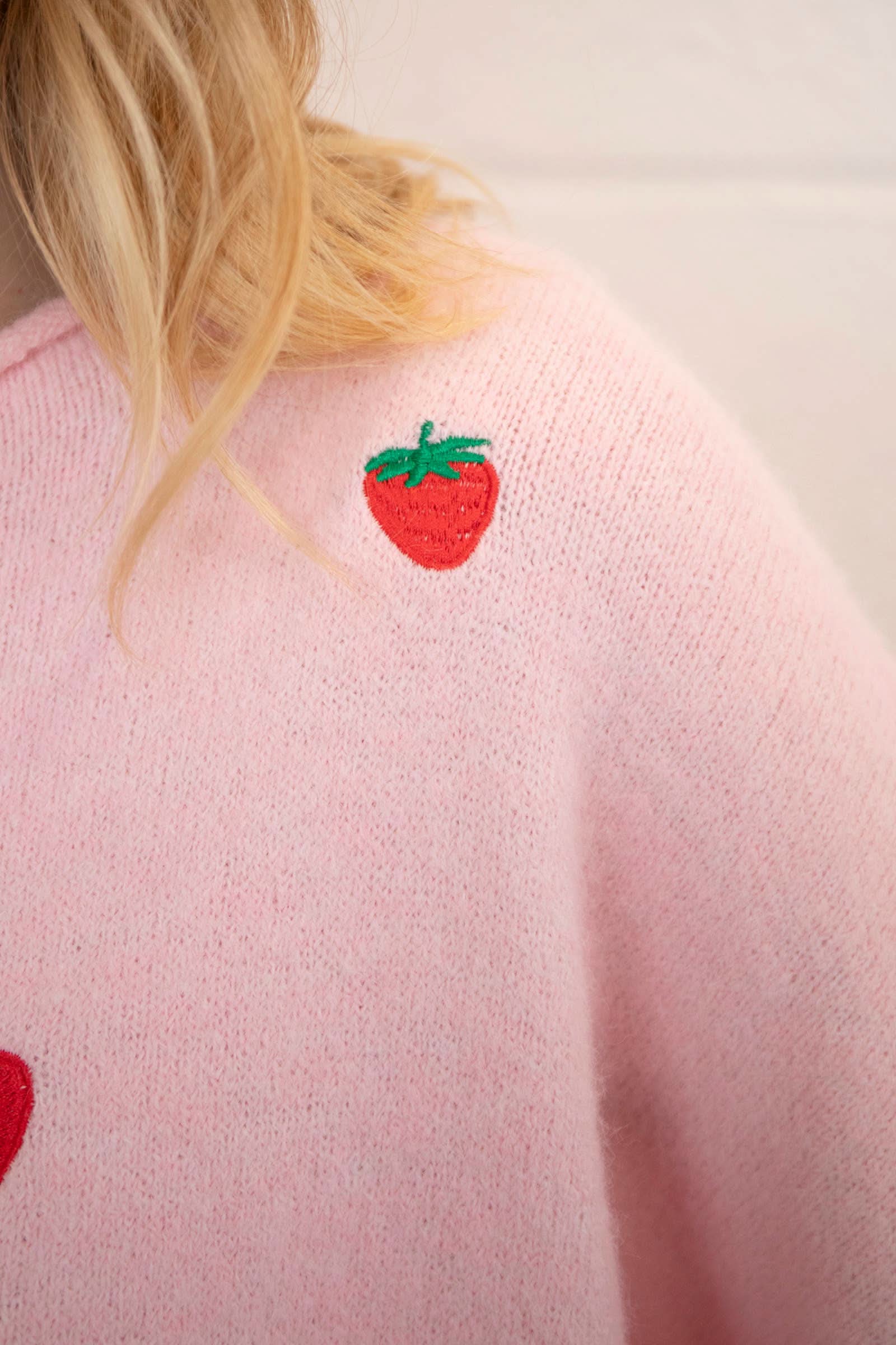 Woman wearing a pink button down cardigan with strawberries