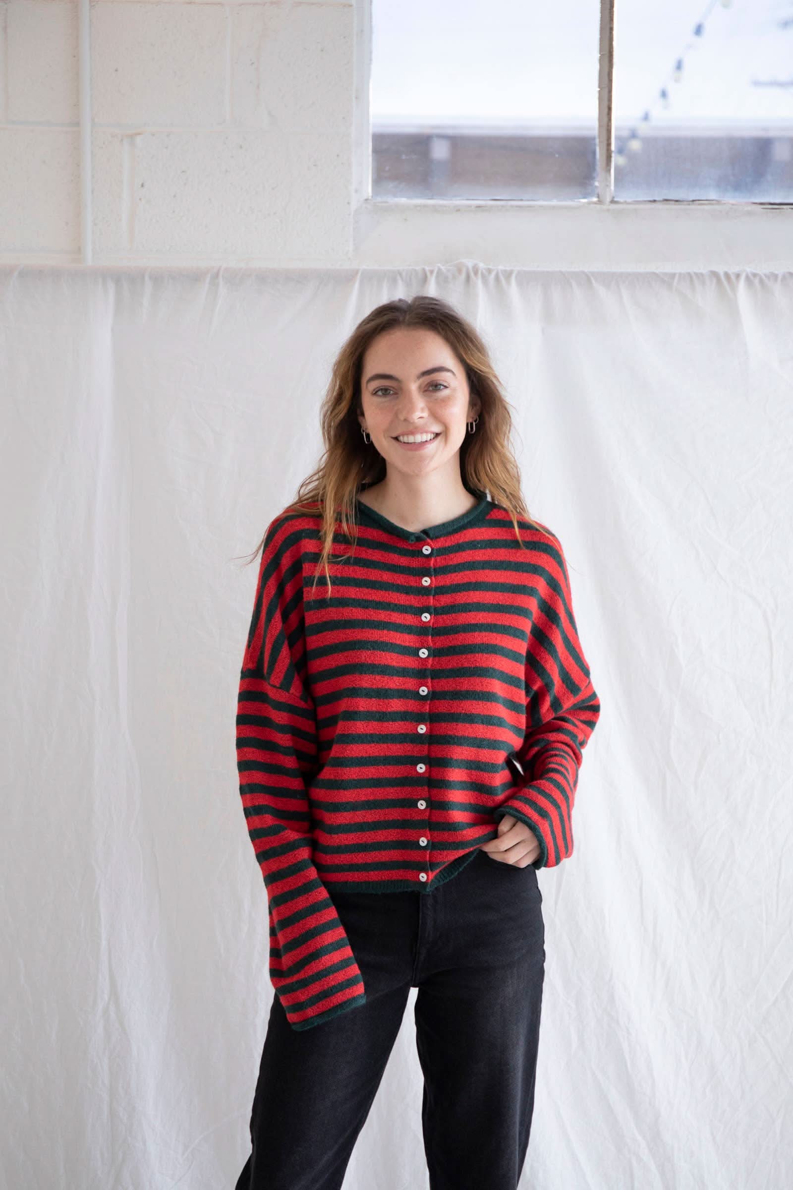 Woman wearing oversized red and forest green stripped cardigan with ivory buttons 