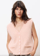 woman wearing a soft oversized pink cardigan vest with buttons