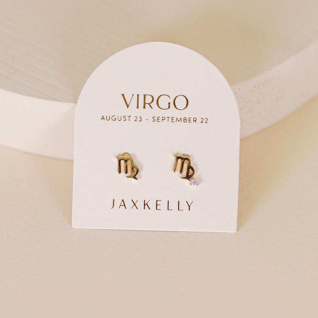 Gold zodiac charm studs in the shape of Virgo astrological sign displayed on earring card