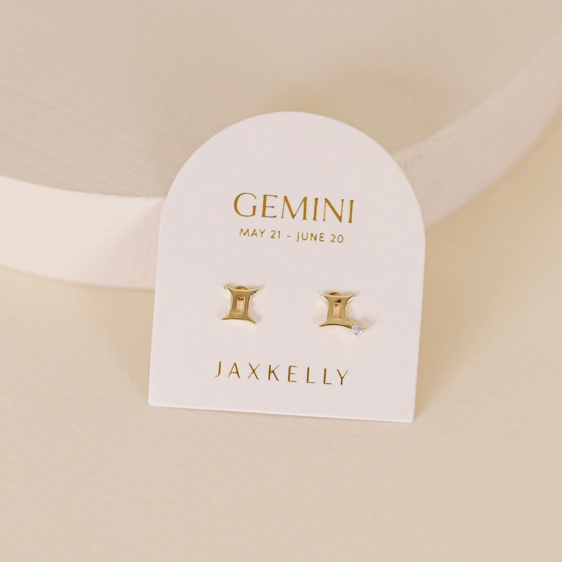 Gold zodiac charm studs in the shape of Gemini astrological sign displayed on earring card