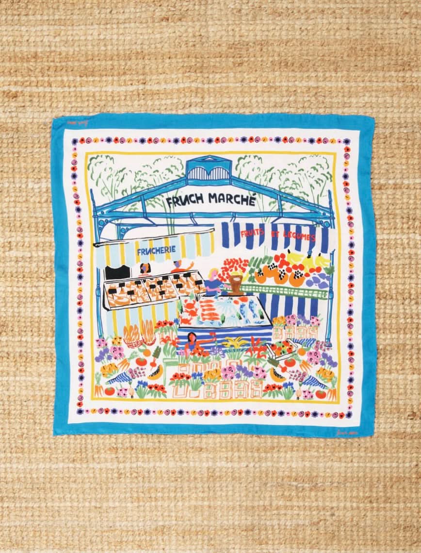 OCEANA silk scarf with blue outline and a farmers market illustration using many colors featuring bread, flower, and fruits 