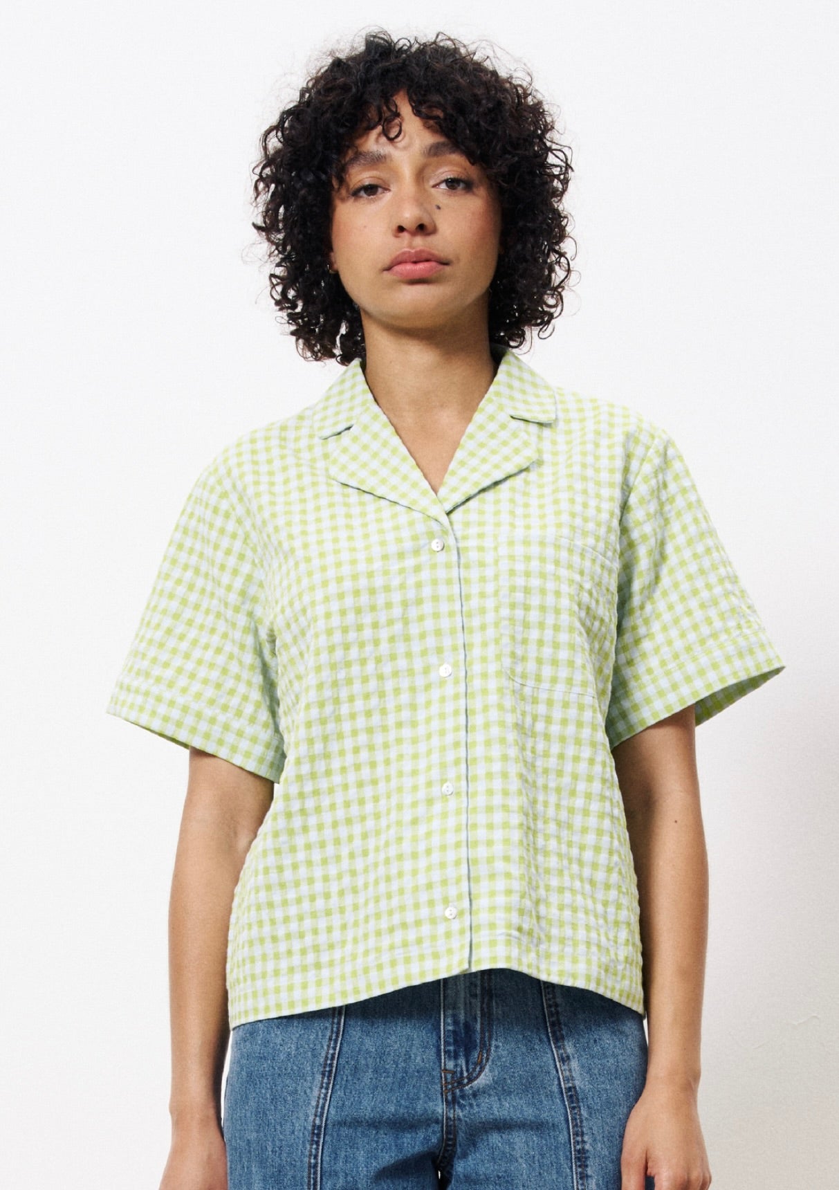 Woman wearing yellow green and white gingham button up cropped blouse with front pocket 