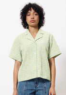 Woman wearing yellow green and white gingham button up cropped blouse with front pocket 