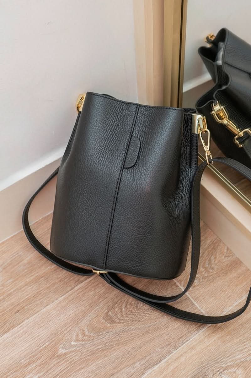 Black leather handbag with gold accents on a wooden floor
