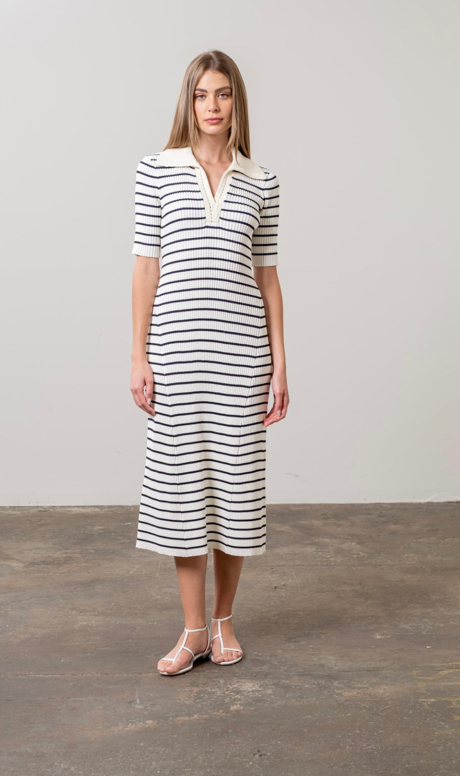 Woman wearing black and white striped midi sweater dress with white collar 