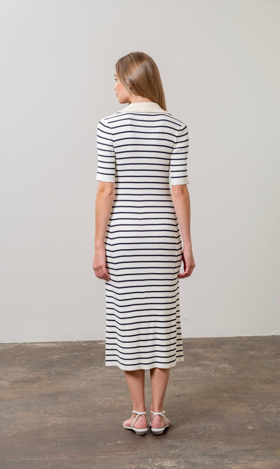 Woman wearing black and white striped midi sweater dress with white collar short sleeves 