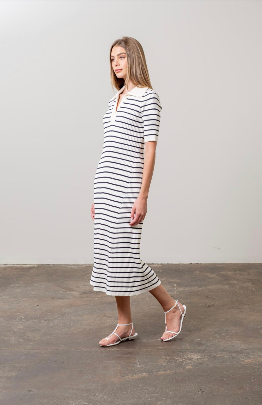 Woman wearing black and white striped midi sweater dress with white collar and short sleeves 