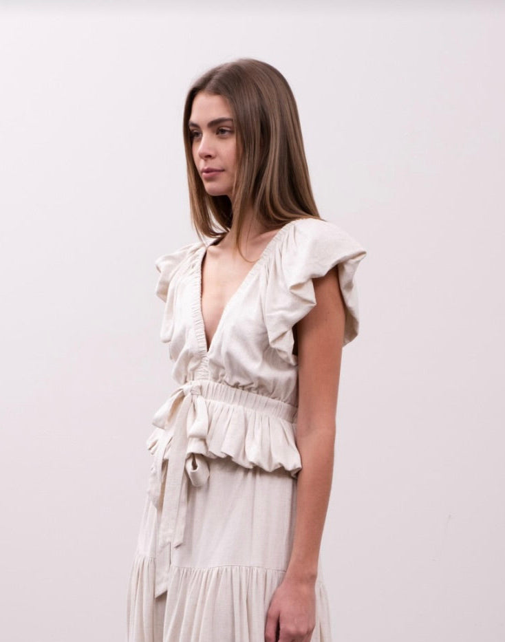 Woman wearing cream beige blouse with delicate ruffle details, bow, and voluminous sleeves