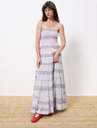 Woman wearing long red white and blue striped strapless dress, smocked on the chest paired with red ballet flats 