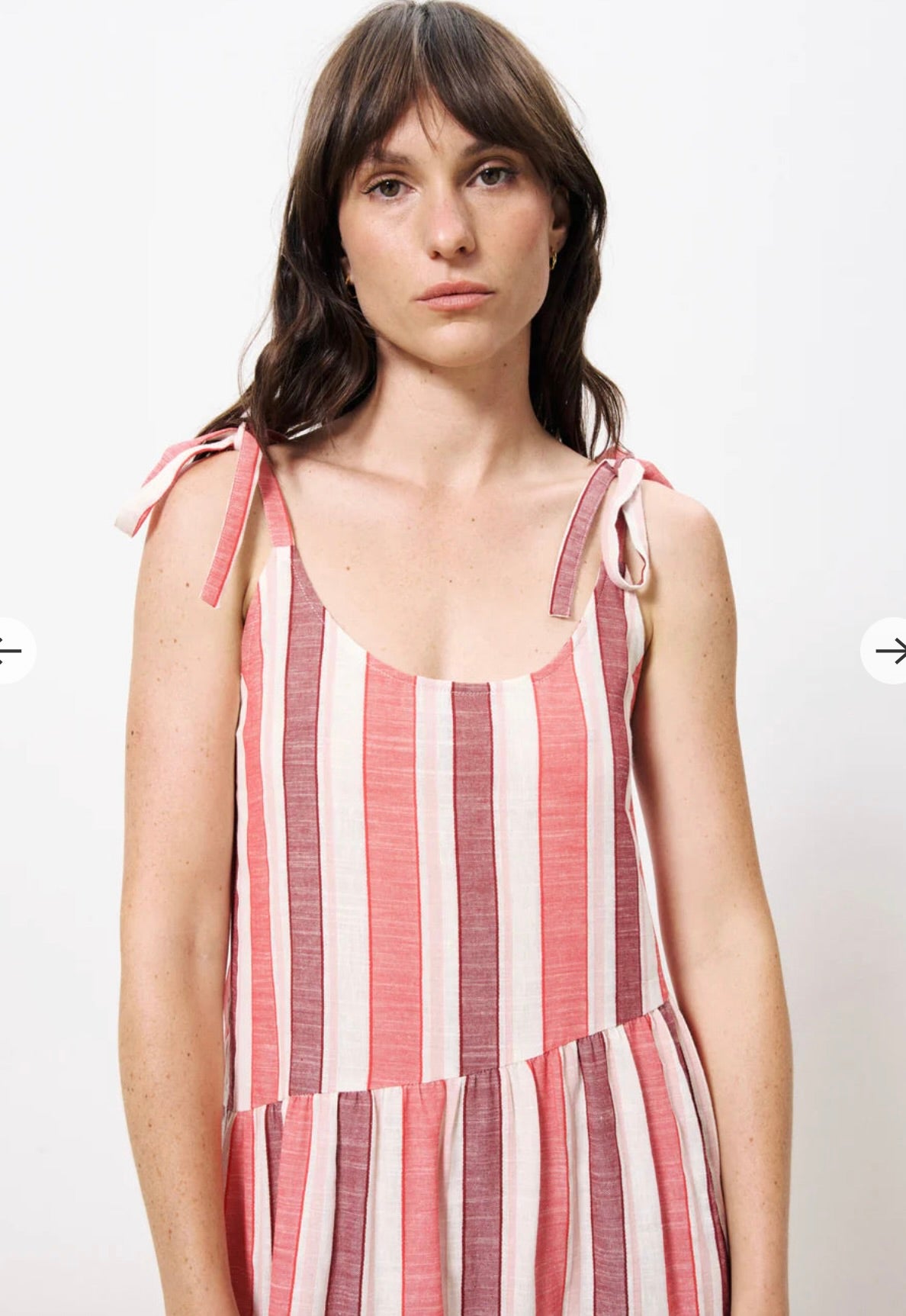 Photo of top half of woman wearing red burgundy and white striped linen dress with thick should ties 