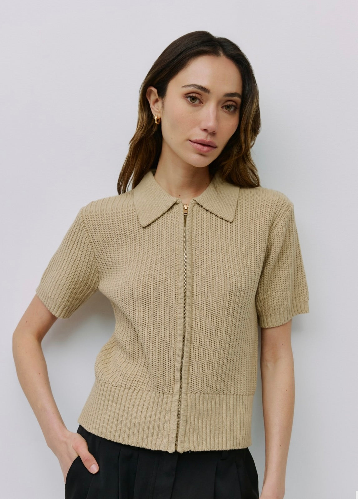 Woman wearing beige short-sleeve open knit top, collared neckline zip front closure