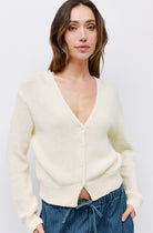 Woman wearing off white knit long sleeve sweater deep v neck with front button closure