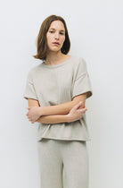 Woman wearing  oatmeal color knit shirt with a relaxed fit and raw roll-up hem and matching pants 