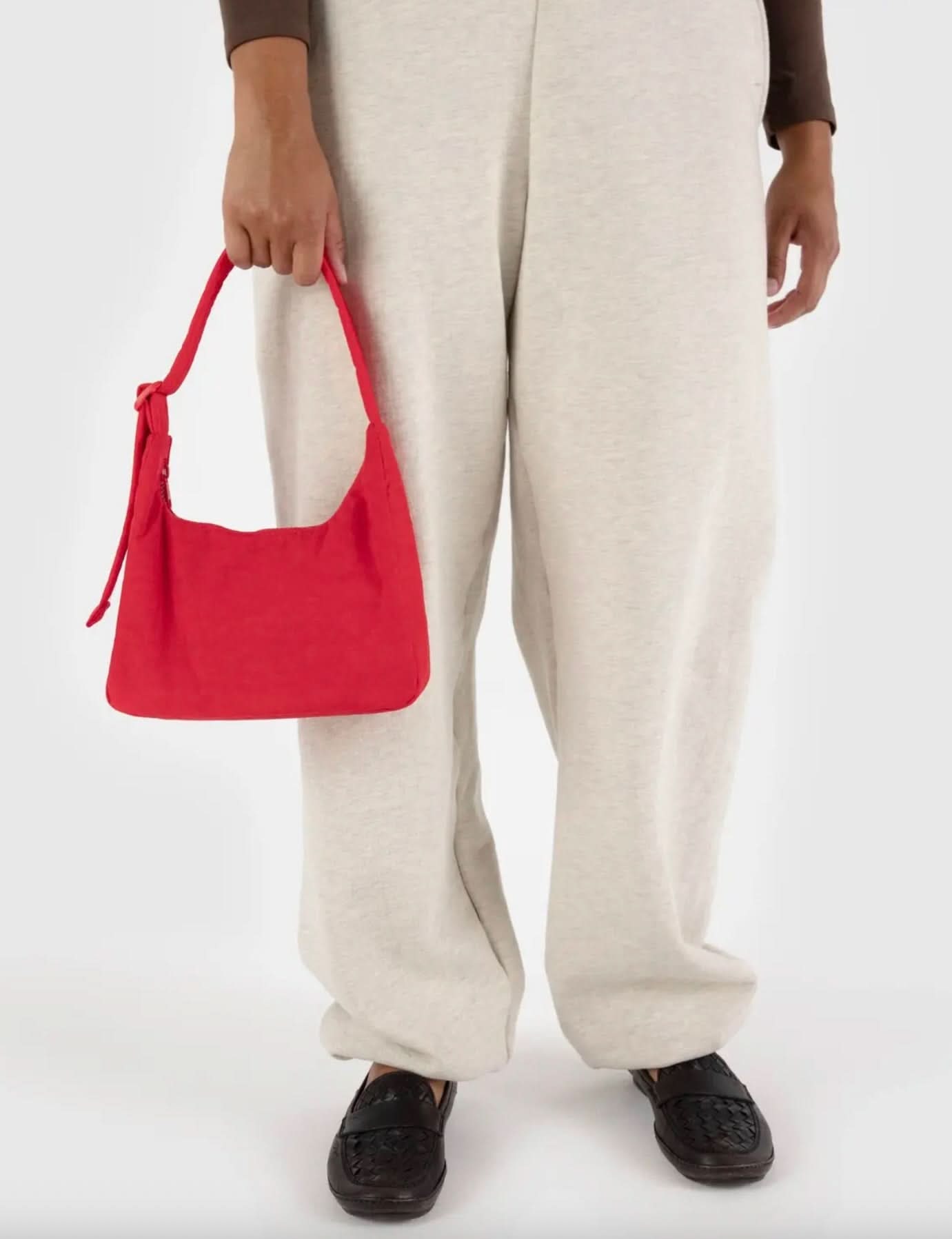 Woman holding Bright candy apple red BAGGU mini nylon shoulder bag 