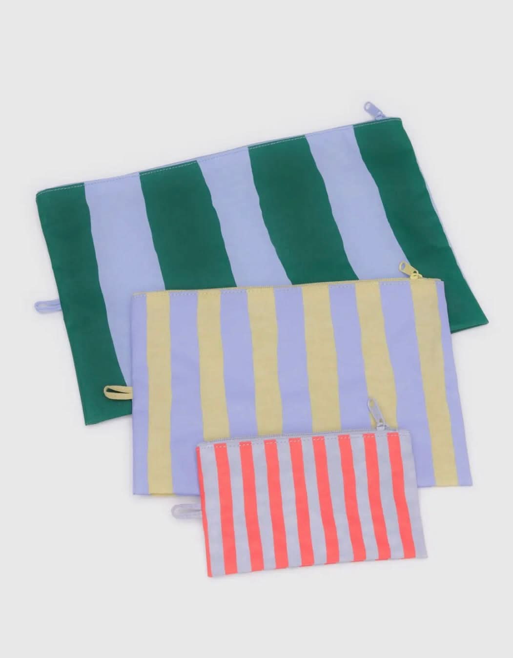 Three BAGGU travel pouch bags in varying sizes the largest is green and blue striped, the medium pouch is blue and yellow, the smallest pouch is blue and red