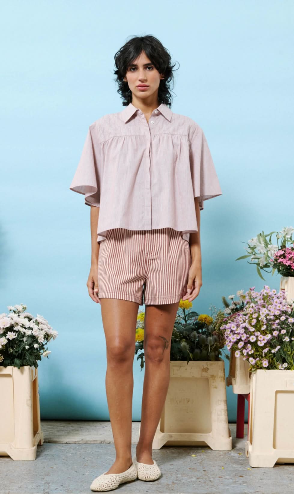 Woman wearing 100% cotton button down, cropped blouse with small vertical stripes 