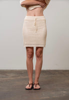 Woman wearing cream beige drawstring crochet mini skirt 