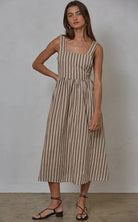 Woman wearing latte brown colored midi dress with vertical blue/black and red striped 