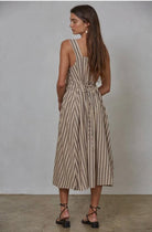 Woman wearing latte brown colored midi dress with vertical blue/black and red striped with waist tie in the back 