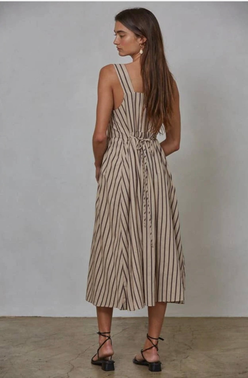 Woman wearing latte brown colored midi dress with vertical blue/black and red striped with waist tie in the back 