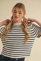 Woman wearing short sleeve knitted black and white striped sweater with dark blue short jean skirt 
