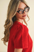 Woman wearing red, fuzzy, short sleeved, button up cardigan
