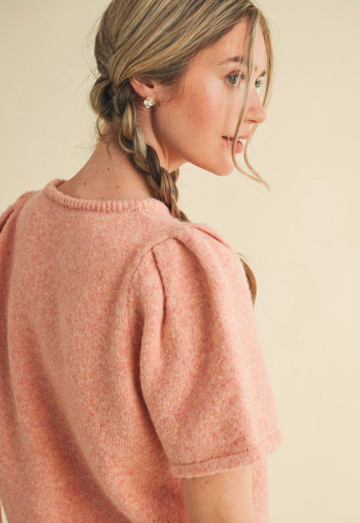 Woman wearing peach pink, fuzzy, short sleeved, button up cardigan